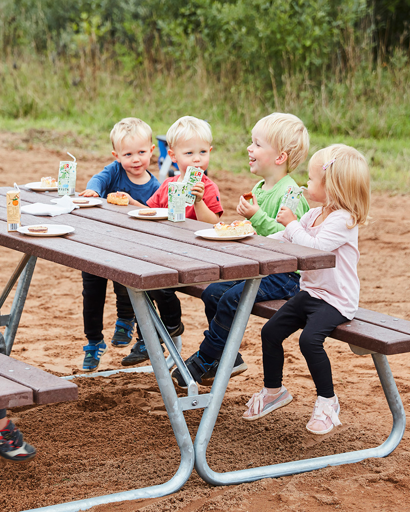 Kinder genießen einen Snack bei einem Picknick Tisch.